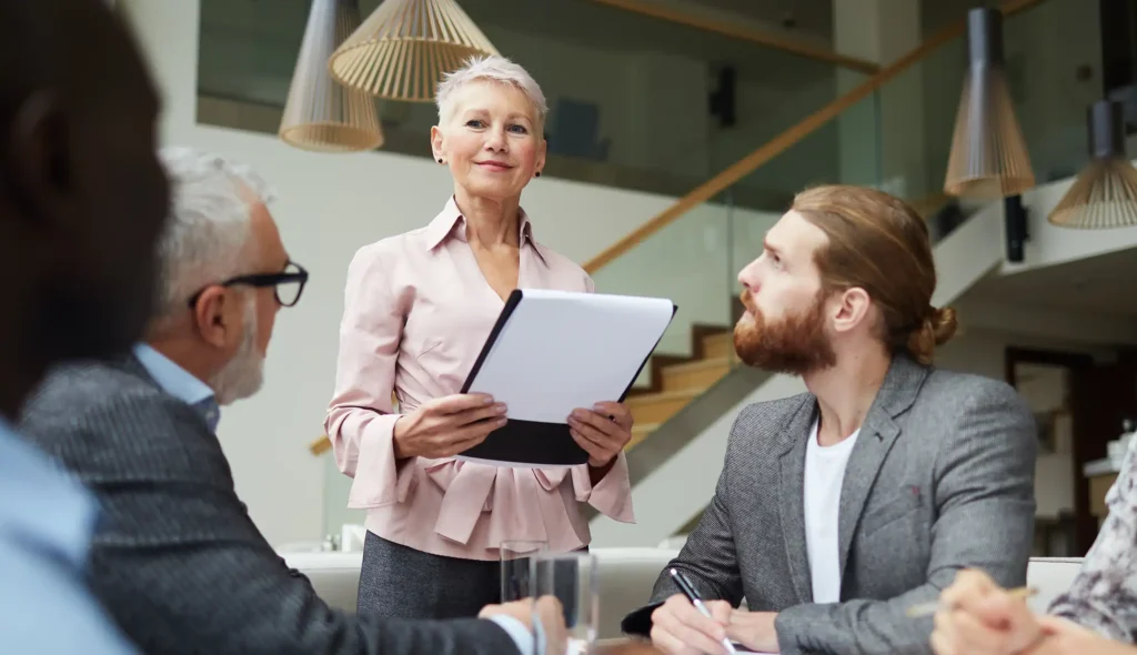 Portrait of modern senior businessman leading meeting with employees in office